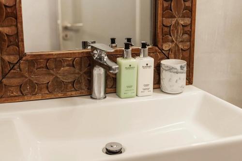 lavabo con 2 botellas de jabón y espejo en Villa LuxL, en Fira