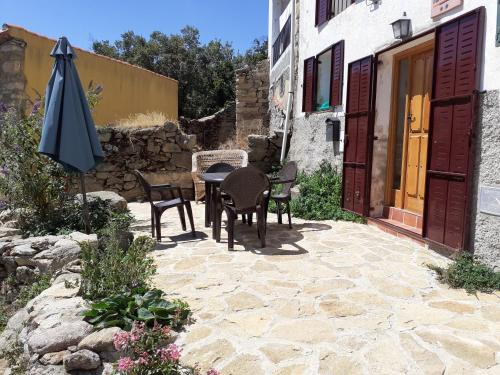 un patio con mesa, sillas y sombrilla en Los Castaños en Solana de ávila