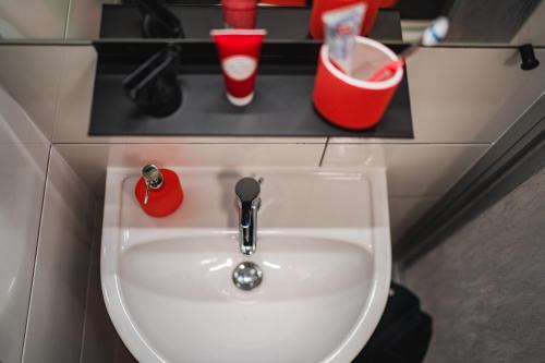 a bathroom sink with two cups on a shelf at Weberhof Ferienapartments in Rostrup am Westufer des Zwischenahner Meers in Bad Zwischenahn