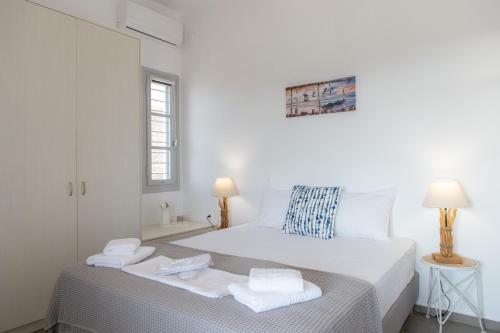 Un dormitorio blanco con una cama con toallas. en Grey House en Exámbela