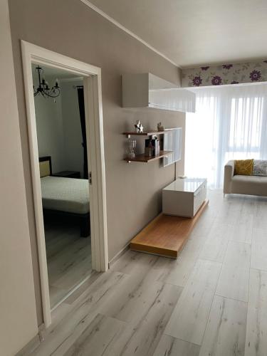 een woonkamer met houten vloeren en een slaapkamer bij Apartament AVANA in Oradea