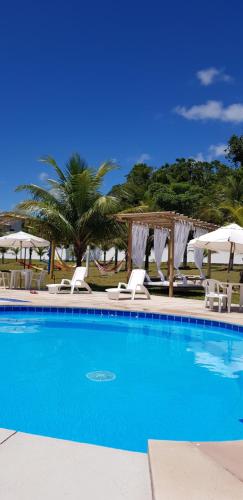 a swimming pool with lounge chairs and umbrellas at Casa7 RCR Green Field - Descanso e Natureza in Arraial d'Ajuda