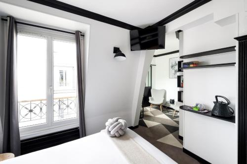 um pequeno apartamento com paredes brancas e uma grande janela em Madrigal em Paris