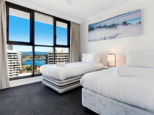 two beds in a room with a large window at Acapulco 2 Bedroom Ocean View Surfers Paradise in Gold Coast