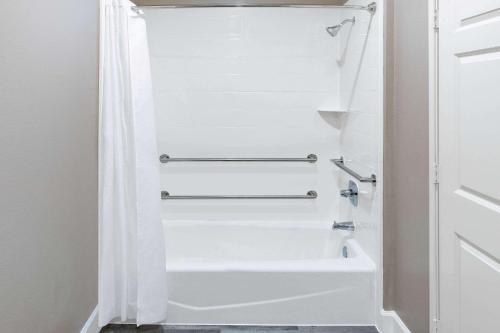 La salle de bains est pourvue d'une baignoire blanche et d'un rideau de douche blanc. dans l'établissement Super 8 by Wyndham Houston NW Beltway 8-West Rd, à Houston