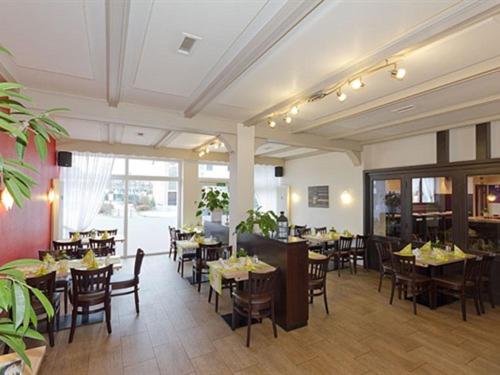 une salle à manger avec des tables et des chaises dans un restaurant dans l'établissement Hotel Fassbender, à Pulheim