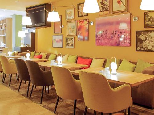 a restaurant with tables and chairs in a room at Mercure Hotel Hannover Mitte in Hannover