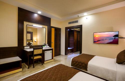 a hotel room with a bed and a desk and a bedroom at Hotel Aadithya in Chennai