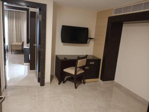 a room with a desk and a chair and a television at Hotel Aadithya in Chennai