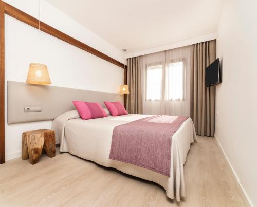 una camera da letto con un grande letto con cuscini rosa di Insotel Club Tarida Playa a Cala Tarida