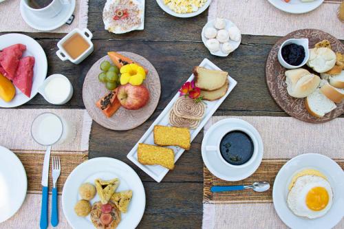 a table with plates of food and cups of coffee at Pousada Brisa Do Porto in Porto De Galinhas