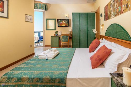 a bedroom with a bed with a green headboard at Hotel Bellevue in Bibione