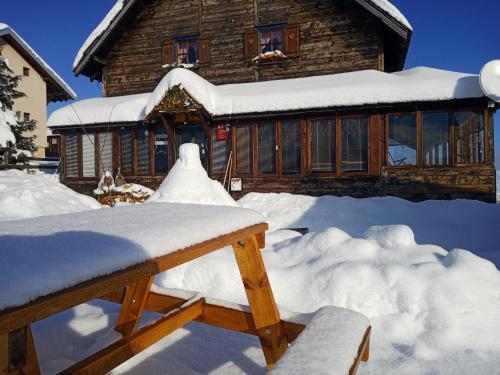 a house covered in snow in front at Planinarski dom "Tornik" Zlatibor in Ribnica