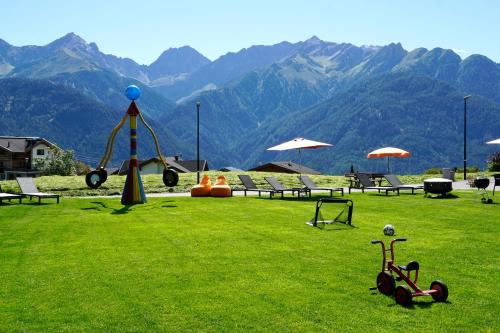 a green field with a playground with mountains in the background at Apart-Hotel Dreisonnenhof in Fiss