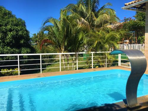 a swimming pool with a fence and palm trees at Pousada Santa Helena in Iriri