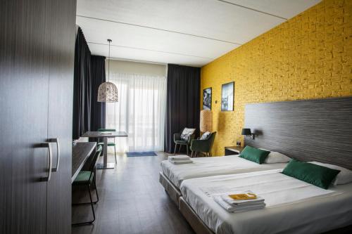 um quarto de hotel com uma cama grande e uma secretária em Strandhotel Vigilante em Makkum