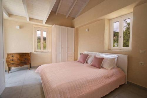 una camera da letto con un grande letto con cuscini rosa di Mathilda's House a Tselendáta