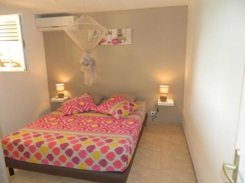 a small bedroom with a bed and two lamps at TI COLIBRI COQUET T2 VUE MER Possibilité repas in Le Robert