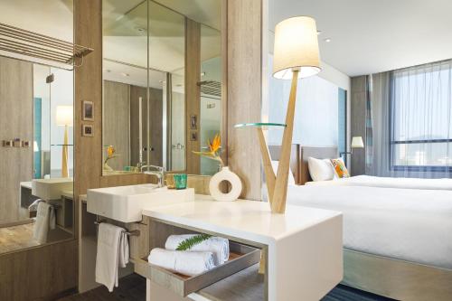 uma casa de banho com um lavatório e uma cama num quarto em Hotel Cham Cham Taitung Caesar Park Hotels & Resort em Taitung City