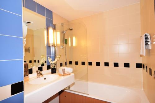 a bathroom with a sink and a shower and a tub at Kyriad Prestige - Bordeaux Aeroport in Mérignac