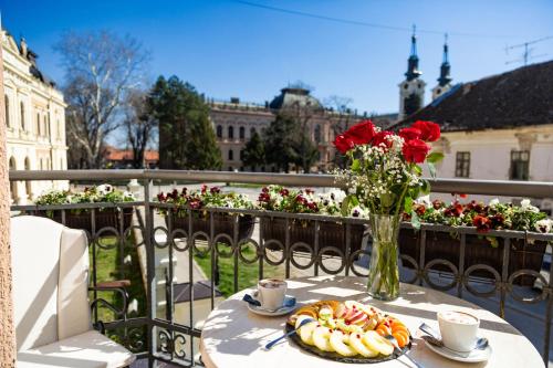 a table with a vase of roses and a plate of food at Premier Prezident Garni Hotel and Spa in Sremski Karlovci