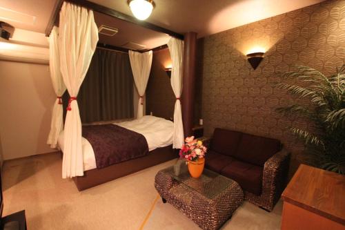 um quarto de hotel com uma cama e um sofá em ホテル シンドバッド滝沢店 Adult Only em Barajima
