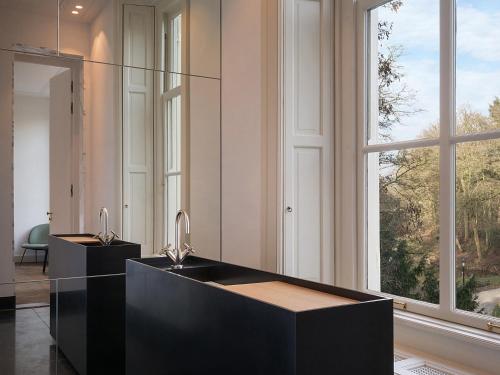 a bathroom with two sinks and a large window at Parc Broekhuizen l Culinair landgoed in Leersum