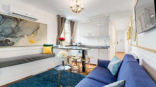 a living room with a blue couch and a kitchen at Luxury 2 Bedroom - Louvre & Champs Elysees in Paris