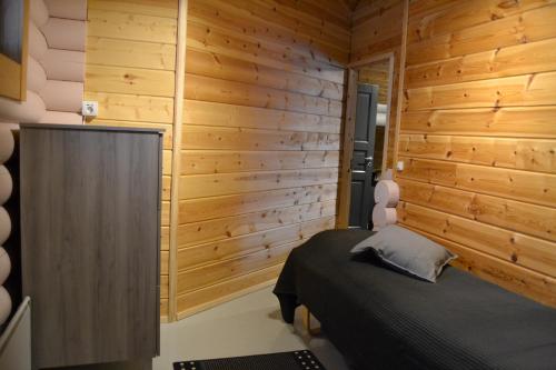 a bedroom with a bed and a wooden wall at Hallanpoika mökki in Hyrynsalmi
