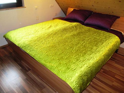 un letto verde in una camera con pavimento in legno di Holiday Home Češnovar a Raka