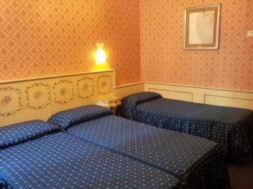two beds in a hotel room with blue sheets at Hotel Diana in Venice