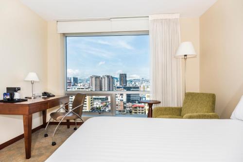 um quarto de hotel com uma cama, uma secretária e uma janela em Holiday Inn Express Quito, an IHG Hotel em Quito