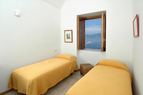 two beds in a room with a window at Amalfi 51 con vista mare, giardino e terrazze in Conca dei Marini