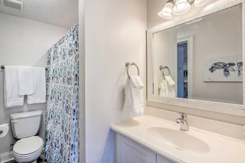 a bathroom with a sink and a toilet and a mirror at Dazzling Mexico Beach Condo - Walk to the Beach! in Mexico Beach