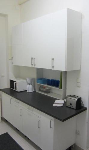 a kitchen with white cabinets and a black counter top at Apartments Johann in Vienna