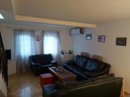 Apartment KARADAK في Kriva Palanka: غرفة معيشة مع كنبتين جلديتين سوداوين وطاولة