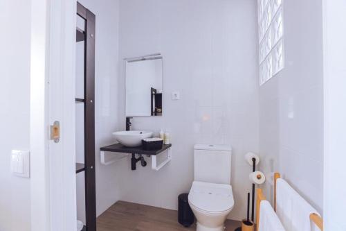 a white bathroom with a toilet and a sink at Downtown Loulé in Loulé