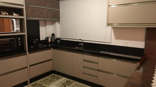 a kitchen with black and white cabinets and a microwave at Fabuloso Apto PIRATUBA in Piratuba