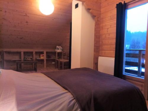 a bedroom with a bed and a large window at Chalet des Brocards in Saint-Maurice-sur-Moselle