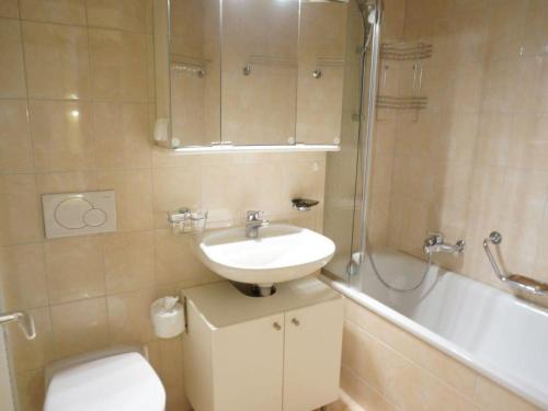 een badkamer met een wastafel, een toilet en een bad bij Apartment La Sarine 13 by Interhome in Gstaad