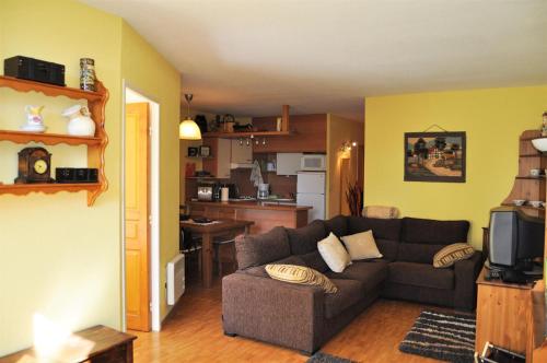 ein Wohnzimmer mit einem Sofa und einer Küche in der Unterkunft Apartamento con piscina en Enveitg in Enveitg