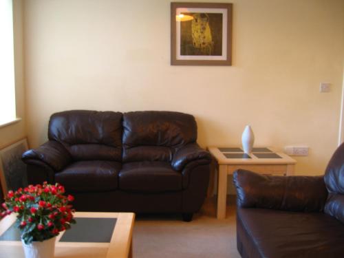 a living room with a leather couch and a table at Simpson's Apartments in Daventry