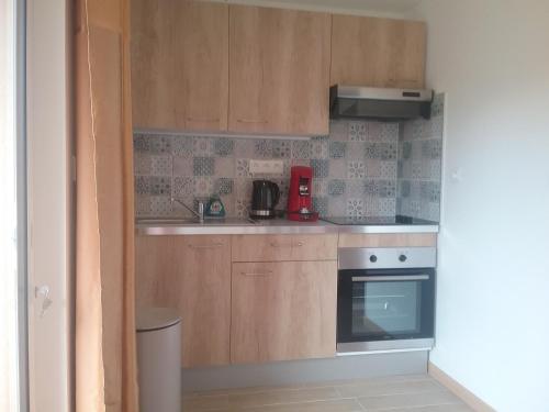 a small kitchen with wooden cabinets and an oven at Chez claudine in Favières