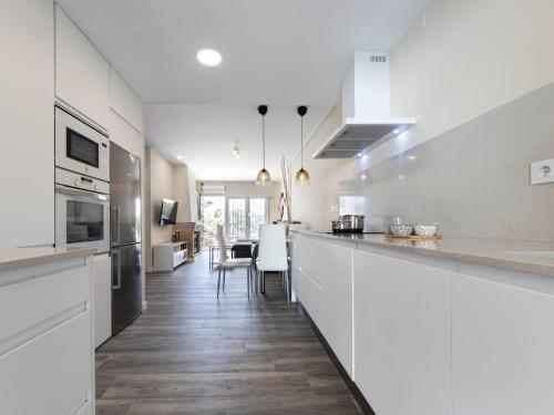 una cocina con armarios blancos y una barra larga en Holiday Home Aeris by Interhome, en Cunit