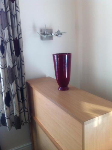 a red vase sitting on top of a wooden dresser at Bridge Hotel Brandon in Brandon