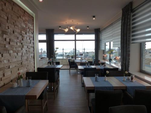 a restaurant with tables and chairs and a brick wall at Strand-Hotel in Dangast