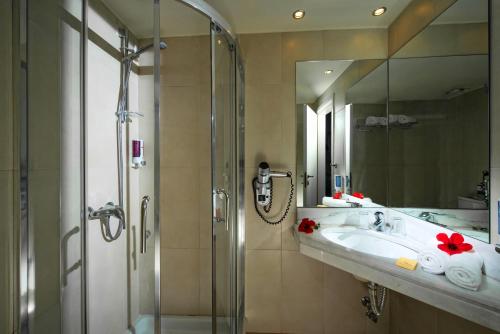 een badkamer met een wastafel en een douche met een spiegel bij Silva Beach Hotel in Chersonissos