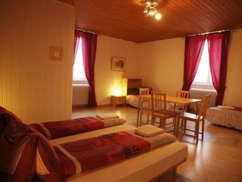 um quarto com duas camas e uma mesa e cadeiras em Hôtel Garni Villa Carmen em La Neuveville