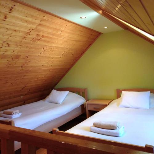 two beds in a attic room with wooden ceilings at Apartment Petra in Mrkopalj