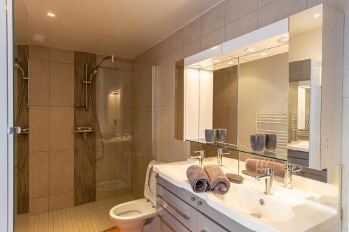 een badkamer met een wastafel, een toilet en een spiegel bij Au Temps Retrouvé in Courcelles